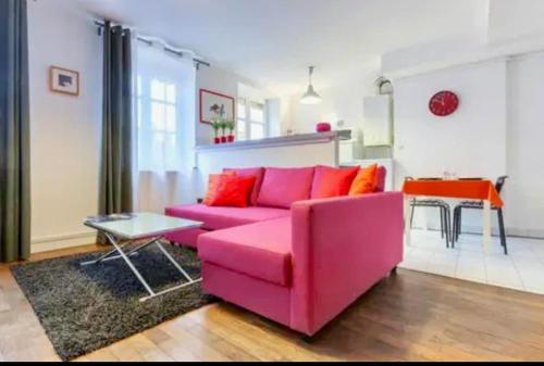 - un canapé rose dans le salon avec une table dans l'établissement Pop Opera Appartement idéal au coeur de lyon 1er, à Lyon