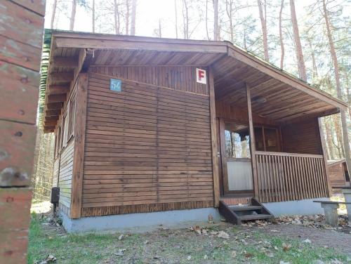 a small wooden building with a door in the woods at Leśna Osada Tęcza Jabłonowiec in Jabłonowiec