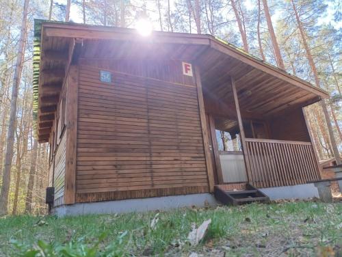 a small wooden cabin in the woods with the sun shining at Leśna Osada Tęcza Jabłonowiec in Jabłonowiec