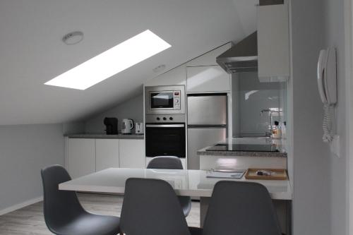a kitchen with a white table and some chairs at Apartamentos do Parque in Vila Real