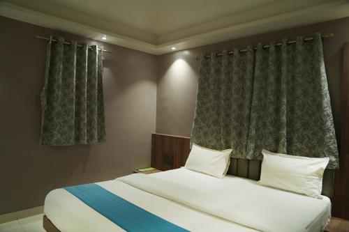 a bedroom with a large white bed and curtains at Hotel Yashoda in Pune