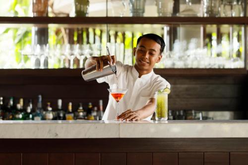 a man is making a drink at a bar at COMO Uma Ubud in Ubud