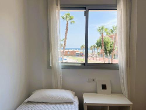 a room with two beds and a window with palm trees at Rose - Primera línea de mar, piscina, wifi, parquing in Cubelles
