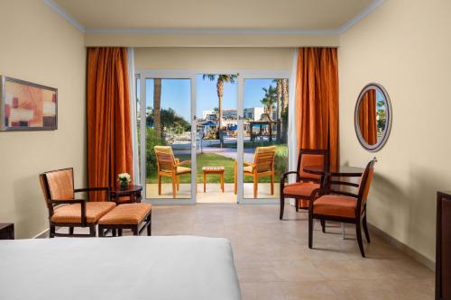 a room with chairs and a table and a balcony at DoubleTree by Hilton Sharks Bay Resort in Sharm El Sheikh