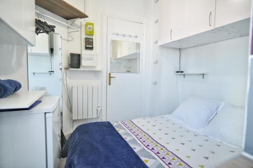 Cette petite chambre blanche comprend un lit et une porte. dans l'établissement Chess Flat - Paris Grands Boulevards, à Paris