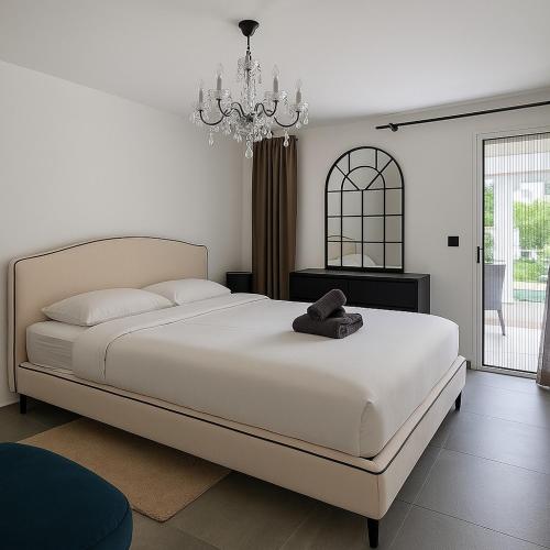 - une chambre avec un grand lit blanc et un lustre dans l'établissement Palm beach apartment with swimming pool in a residence, à Cannes