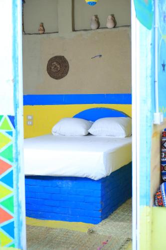 a bedroom with a bed with blue and yellow at Mama Africa Camp in Luxor