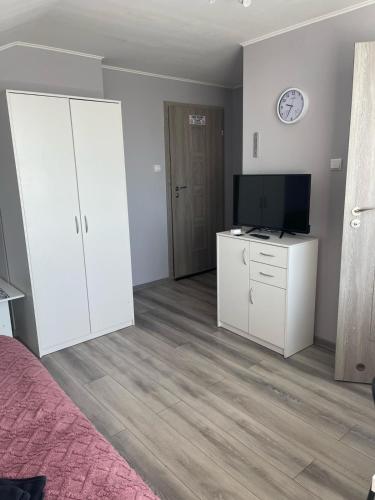 a bedroom with white cabinets and a flat screen tv at Dom Gościnny "Zawiśle" in Włocławek