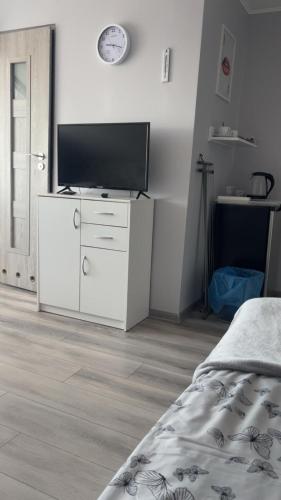 a bedroom with a white dresser with a television on it at Dom Gościnny "Zawiśle" in Włocławek