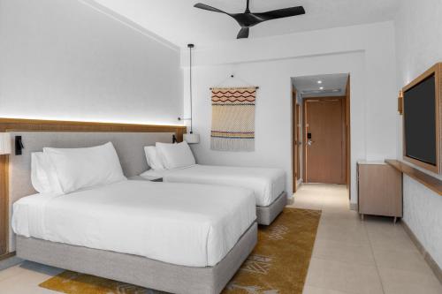a hotel room with two beds and a television at DoubleTree by Hilton Sharks Bay Resort in Sharm El Sheikh