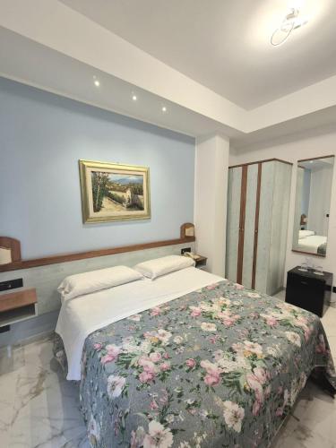 a bedroom with a large bed with a floral blanket at Hotel Condor in Taormina