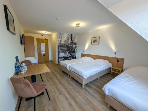um quarto de hotel com duas camas e uma mesa em Hotel B&B d'Olde Smidse em Giethoorn