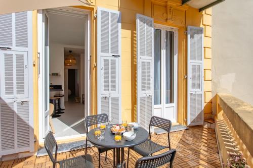 d'une terrasse avec une table, des chaises et des volets blancs. dans l'établissement #35 Suite Carlone 5min from the beach AC & Terrace, à Nice
