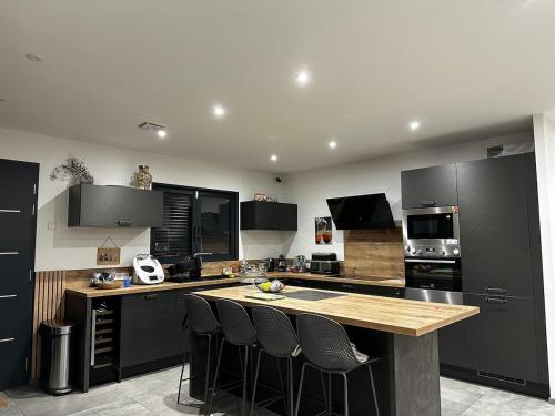 une cuisine avec des appareils électroménagers noirs et un comptoir avec des tabourets de bar dans l'établissement Magnifique Villa avec piscine et jacuzzi, à Alata