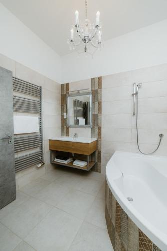 a bathroom with a tub and a sink and a chandelier at Ady54 in Tata