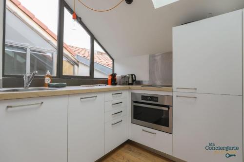 une cuisine avec des placards blancs et une grande fenêtre dans l'établissement Dv7 Rooftop - Jean Jaurès - Métro Gare, à Toulouse