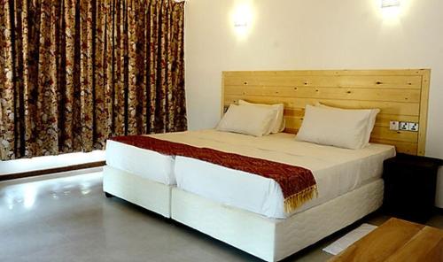 ein Schlafzimmer mit einem großen Bett mit einem hölzernen Kopfteil in der Unterkunft Mangi's Tranquil Bangalows in Pinnawala