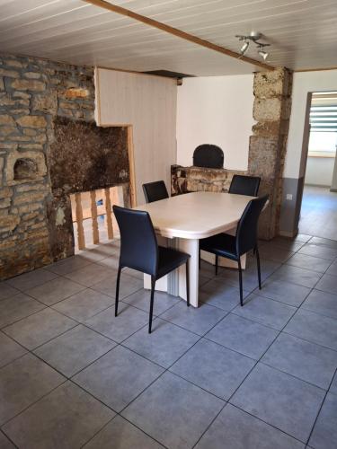 une table et des chaises dans une pièce avec un mur en pierre dans l'établissement Repos, à Les Verrières-de-Joux