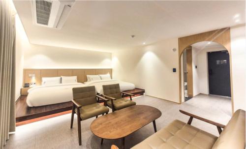 a hotel room with a bed and a table and chairs at H avenue Hotel Jeonju Deokjin in Jeonju