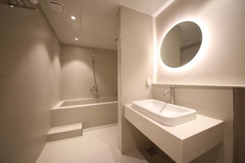 a white bathroom with a sink and a mirror at H avenue Hotel Jeonju Deokjin in Jeonju