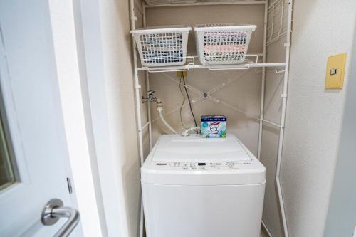 a small laundry room with a washer and dryer at 6th floor 602 with elevator, 700 meters walk from Nishi-Shinjuku Gochome 4 minutes to Shinjuku, 75 square meters plus 30 square meters of large balcony in Tokyo