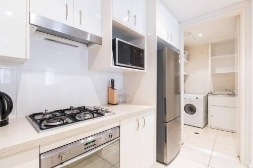 a white kitchen with a stove and a microwave at Coastal Bliss 2 Bedroom Apartment in Gold Coast