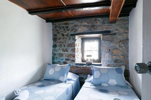 a bedroom with two beds in a stone wall at Cosy House in Isongo in Isongo