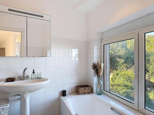 La salle de bains est pourvue d'un lavabo, d'une baignoire et d'une fenêtre. dans l'établissement Villa Mimosa 150 m from Pinarello Beach, à Zonza