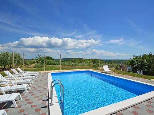 a swimming pool with white lounge chairs around it at Family villa in Buje with pool and sea view in Buje