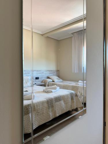 two beds in a room with a mirror at Pension Reconquista in Cangas de Onís