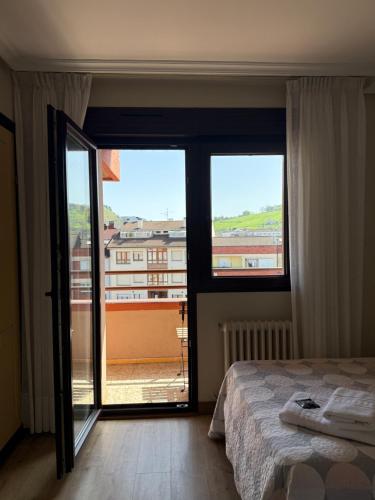a bedroom with a bed and a large window at Pension Reconquista in Cangas de Onís
