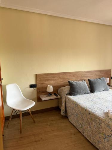 a bedroom with two beds and a white chair at Pension Reconquista in Cangas de Onís