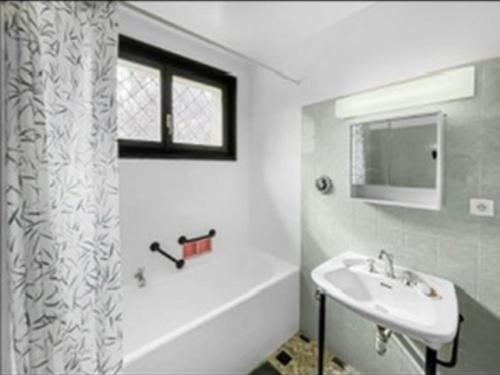 een badkamer met een wastafel en een douchegordijn bij La maison du bonheur à Talloires in Talloires