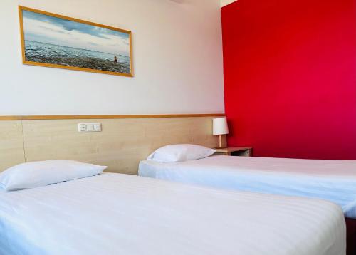 two beds in a hotel room with a red wall at Green Park Hotel Klaipeda in Klaipėda