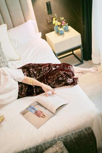 a woman laying on a bed reading a book at Hotel Regina in Madrid
