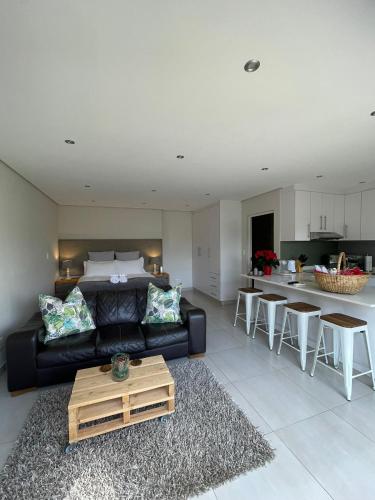 a living room with a black couch and a kitchen at Luxury Self Catering Studio in Eco Estate in Ballito