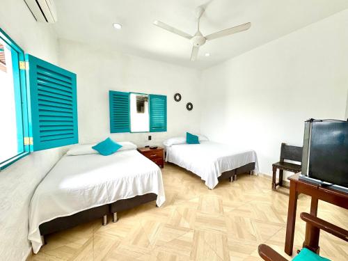 a bedroom with two beds and blue shuttered windows at Plaza Blanca in Doradal