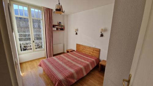 une petite chambre avec un lit et une fenêtre dans l'établissement T3 centre-ville Bagnères-de-Luchon, à Luchon