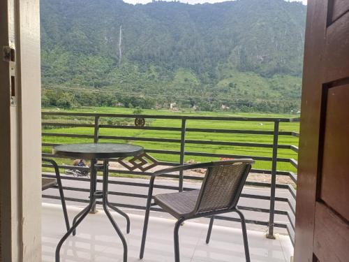 a table and chair on a balcony with a view at GAROGA Guest House in Ambarita