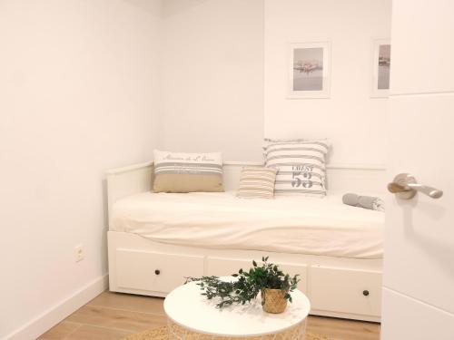 a white bedroom with a bed with a table at Iturrama Nomada loft by Clabao in Pamplona