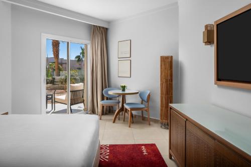 a hotel room with a bed and a table and chairs at DoubleTree by Hilton Sharks Bay Resort in Sharm El Sheikh