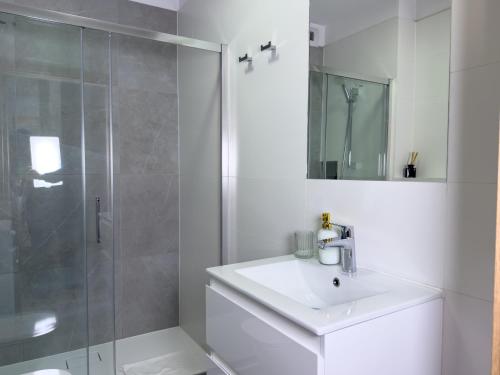 a white bathroom with a sink and a shower at URBAN APARTMENTS PREMIUM, Opolska 10 No 91, Free Garage, Self Check-in in Katowice