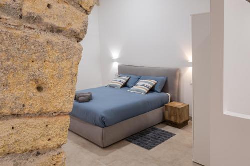 a bed in a room next to a stone wall at Tarchi Apartament in Tarquinia