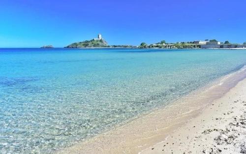 a beach with the ocean and a lighthouse in the background at Casa House Villa Chiara in Pula