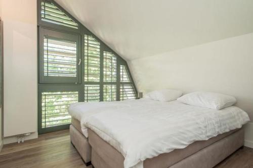 a white bed in a room with two windows at Villa Koperwiek in Egmond aan den Hoef