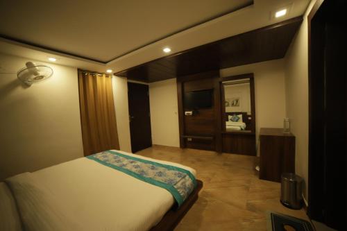 a bedroom with a bed and a television in it at Aman The Lake Side Nainital in Nainital
