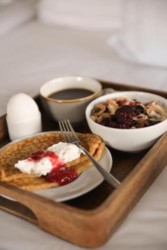 a tray with a plate of food and a bowl of fruit at Quality Hotel The Mill in Malmö