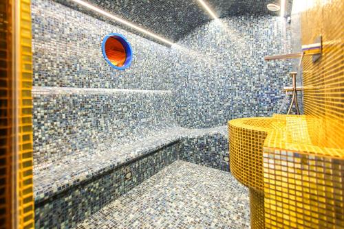 a bathroom with a shower with blue mosaic tiles at Carat Hotel Yerevan in Yerevan
