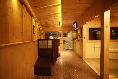 a man standing at a counter in a room with wooden walls at Aman The Lake Side Nainital in Nainital