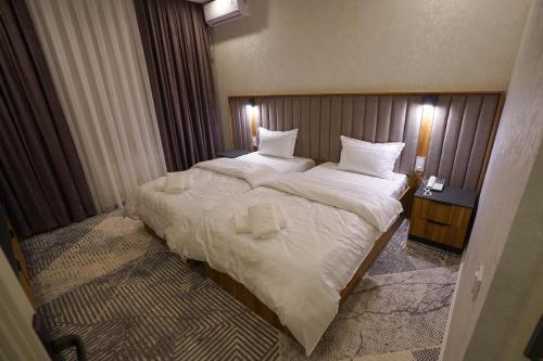 een slaapkamer met een groot bed met witte lakens en kussens bij Florence Hotel in Jizzax